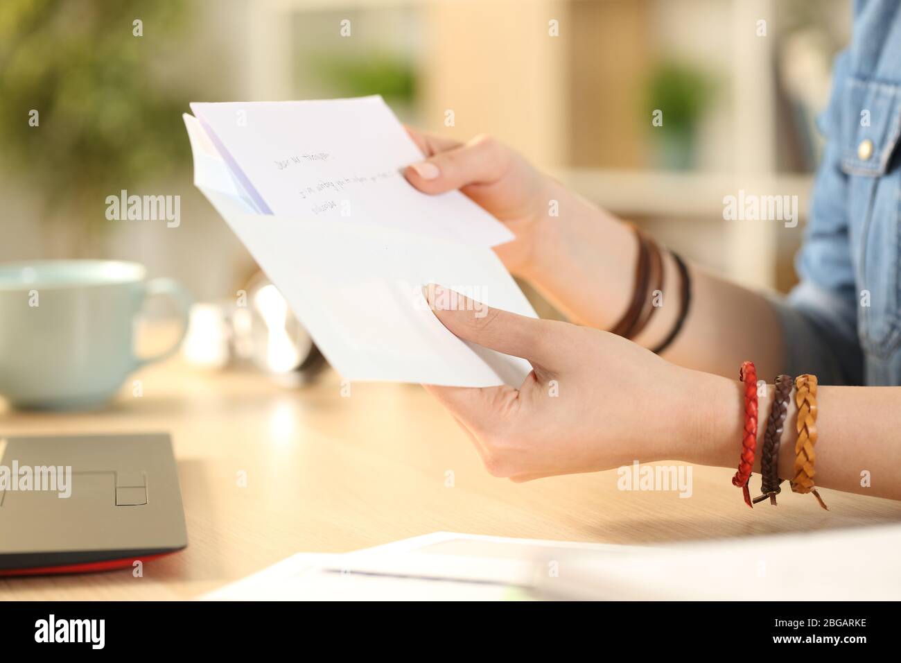 Nahaufnahme von Student Mädchen Hand setzen Brief auf einem Umschlag auf einem Schreibtisch zu Hause Stockfoto