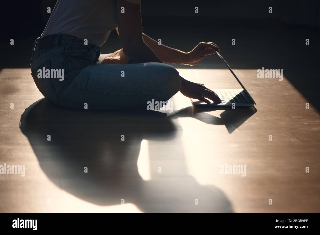 Zugeschnittenes Bild von Frau, die auf dem Boden sitzt und den Laptop schließt. Stockfoto