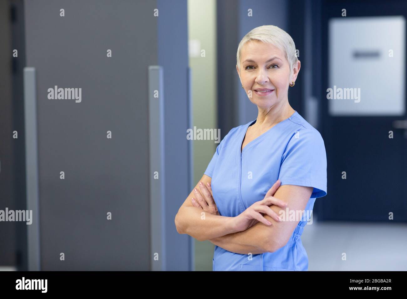 Porträt einer positiv-Reifen Krankenschwester auf dem Flur einer modernen Klinik mit Blick auf die Kamera. Medizinisches Personal Stockfoto