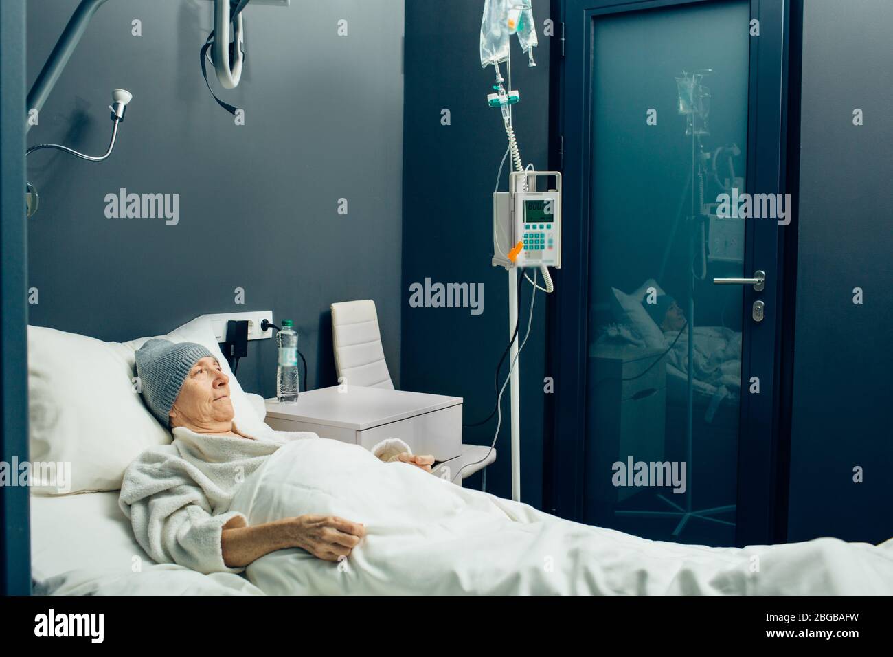 Ältere Frau in einer onkologischen Klinik, die eine Chemotherapie erhält. Infusion für Chemotherapie. Krebs. Onkologie Stockfoto