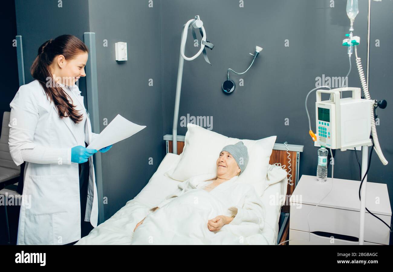 Onkologe, die sich mit positiven Tests eines älteren Patienten in einer onkologischen Abteilung befreunden. Weibliche Patientin positiv während der Krebsbehandlung. Infusionsanschluss für Stockfoto