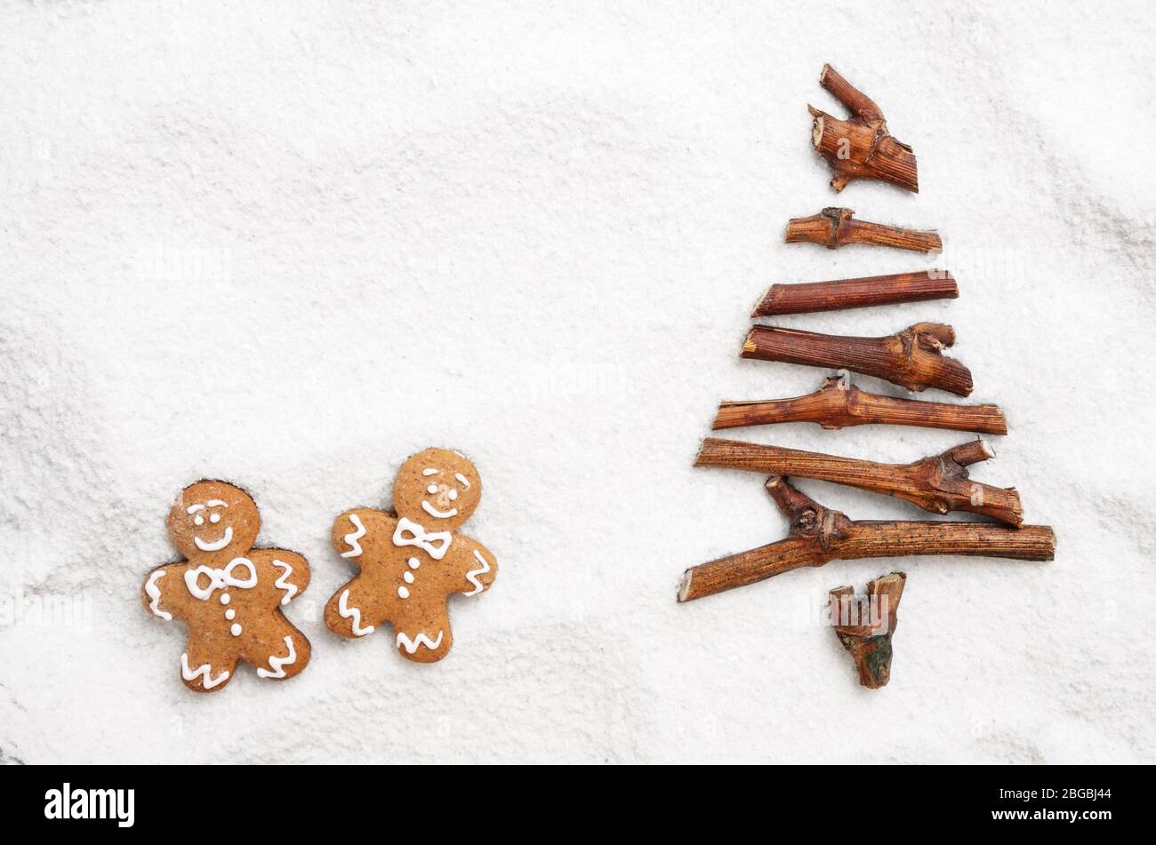 Flach stilisierte Weihnachtsbaum von kleinen Zweigen und Gingerbread man Cookies auf Schnee Hintergrund. Platz für Text Stockfoto
