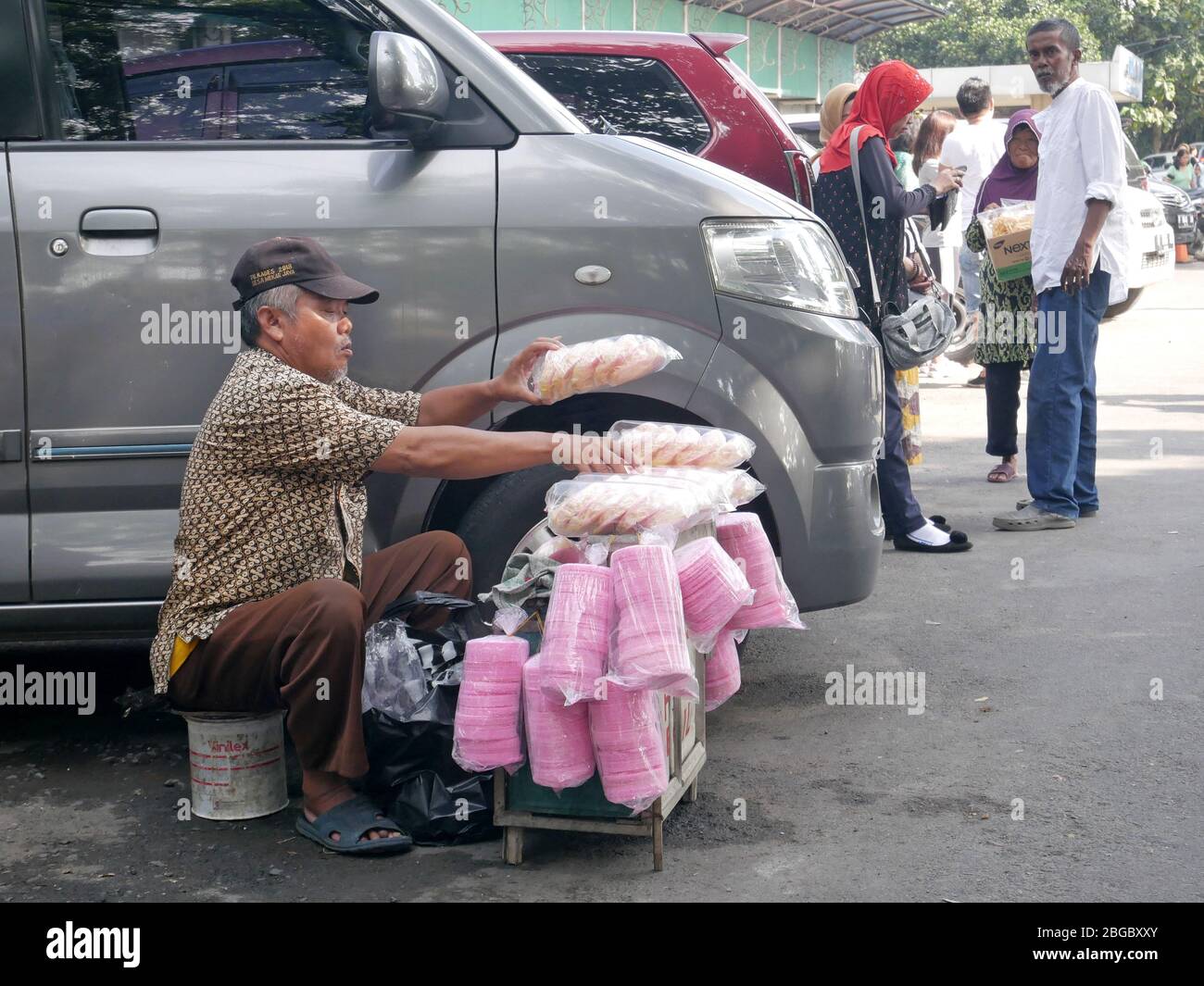 Ein Cracker-Verkäufer putzt seine Ware neben einem Auto auf einem Parkplatz auf. Stockfoto