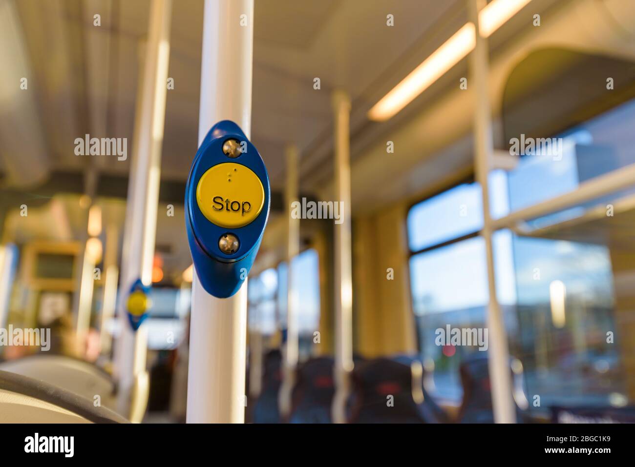 Stopp-Taste an einem Bus. Gelber runder Knopf auf blauem Hintergrund in einer Straßenbahn. Edinburgh, Schottland. Stockfoto