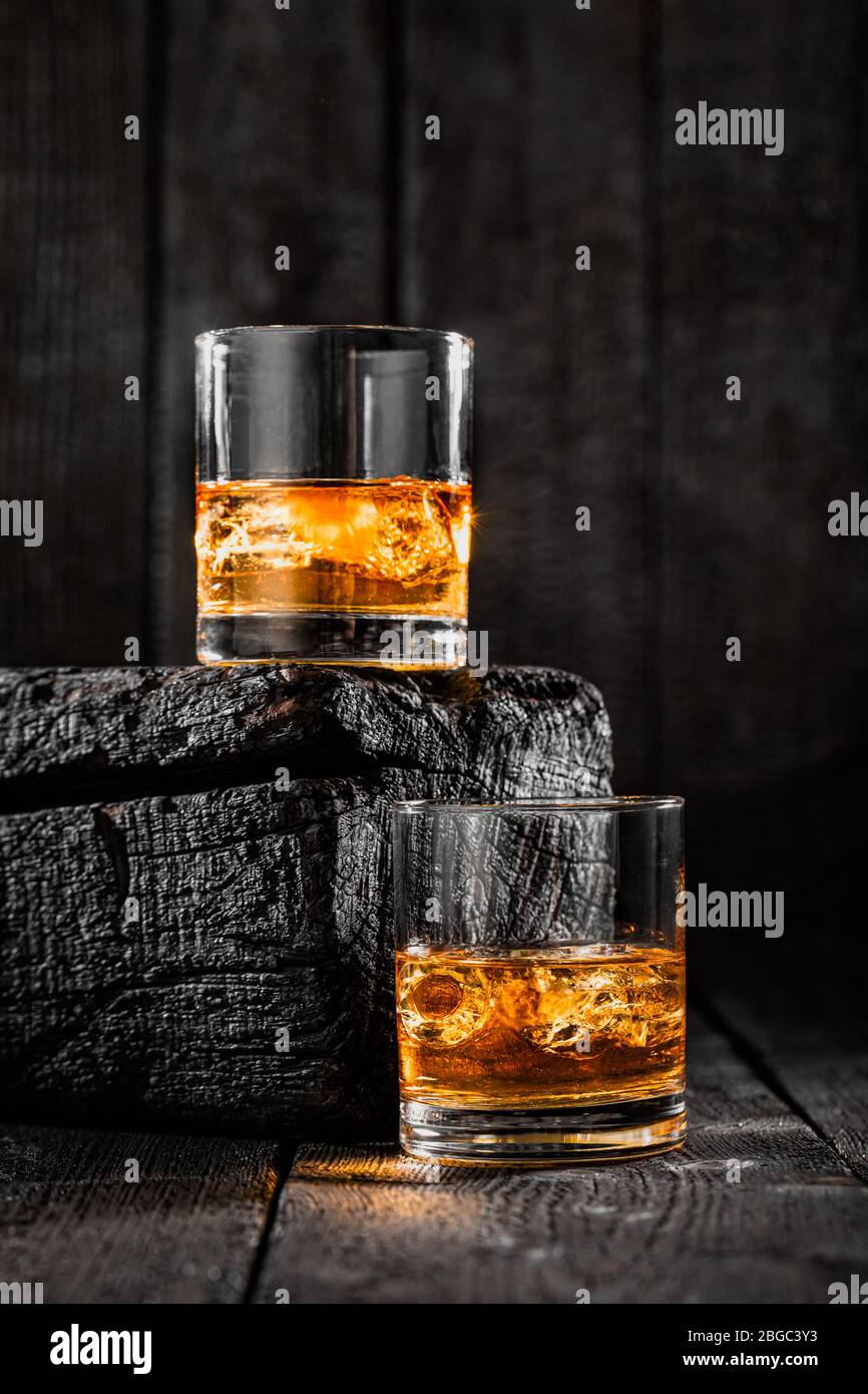 Zwei Gläser Whisky mit Eis auf verbranntem Holz Stockfoto