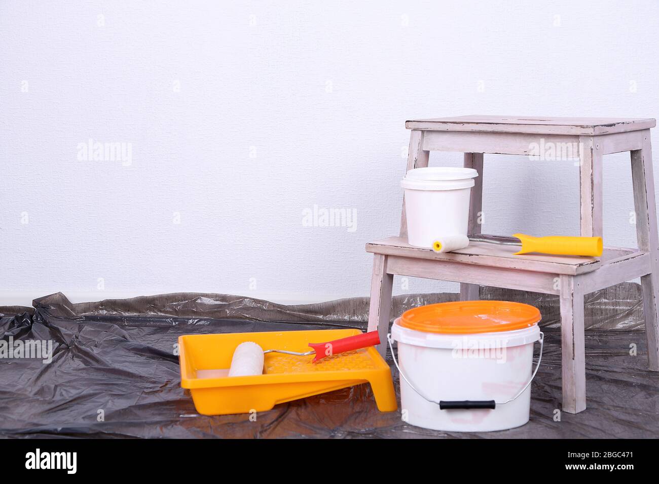 Eimer mit Farbe und Leiter auf Wand Hintergrund. Konzeptuelles Foto von Reparaturarbeiten im Raum Stockfoto