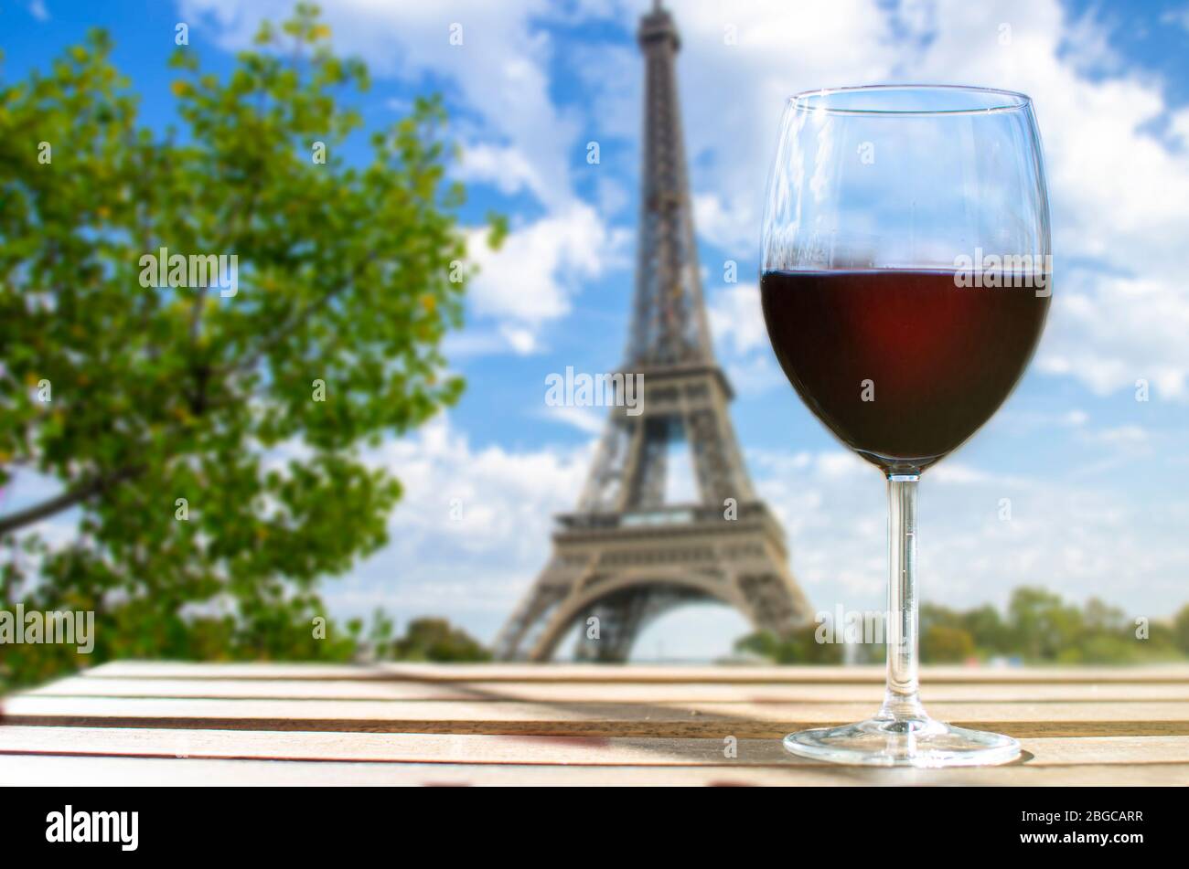 Glas Wein auf dem Eiffelturm verwischt den Hintergrund. Sonniger Blick auf das Glas Rotwein mit Blick auf den Eiffelturm in Paris, Frankreich Stockfoto