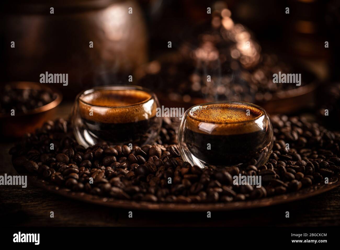 Espresso in doppelwandigen Glasbechern auf Kaffeebohnen Hintergrund, dunkles Bild Stockfoto