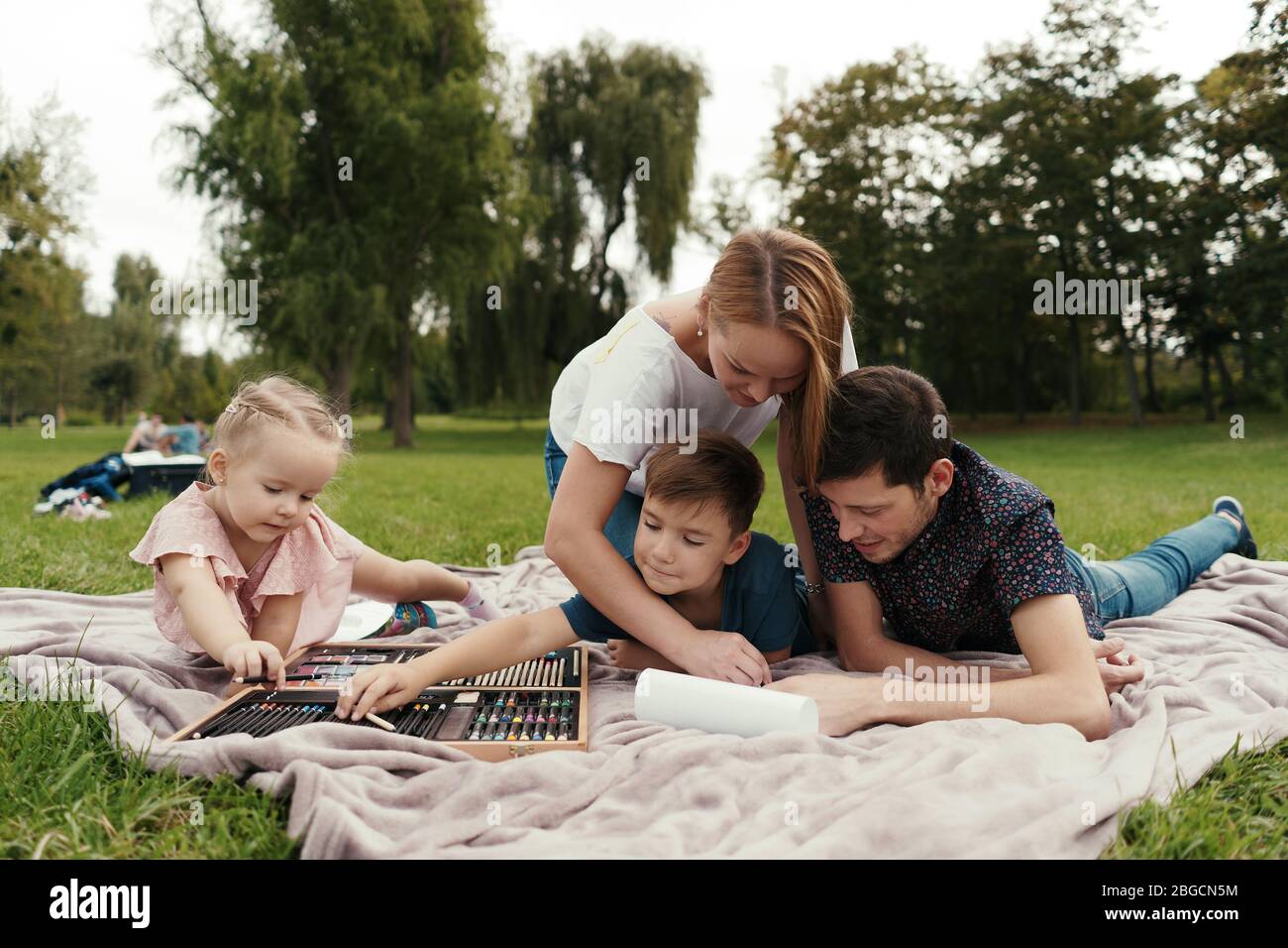 Schöne Familie, Mutter, Vater, Sohn und Tochter verbringt Zeit zusammen, Zeichnung in der Natur auf der Decke liegen Stockfoto
