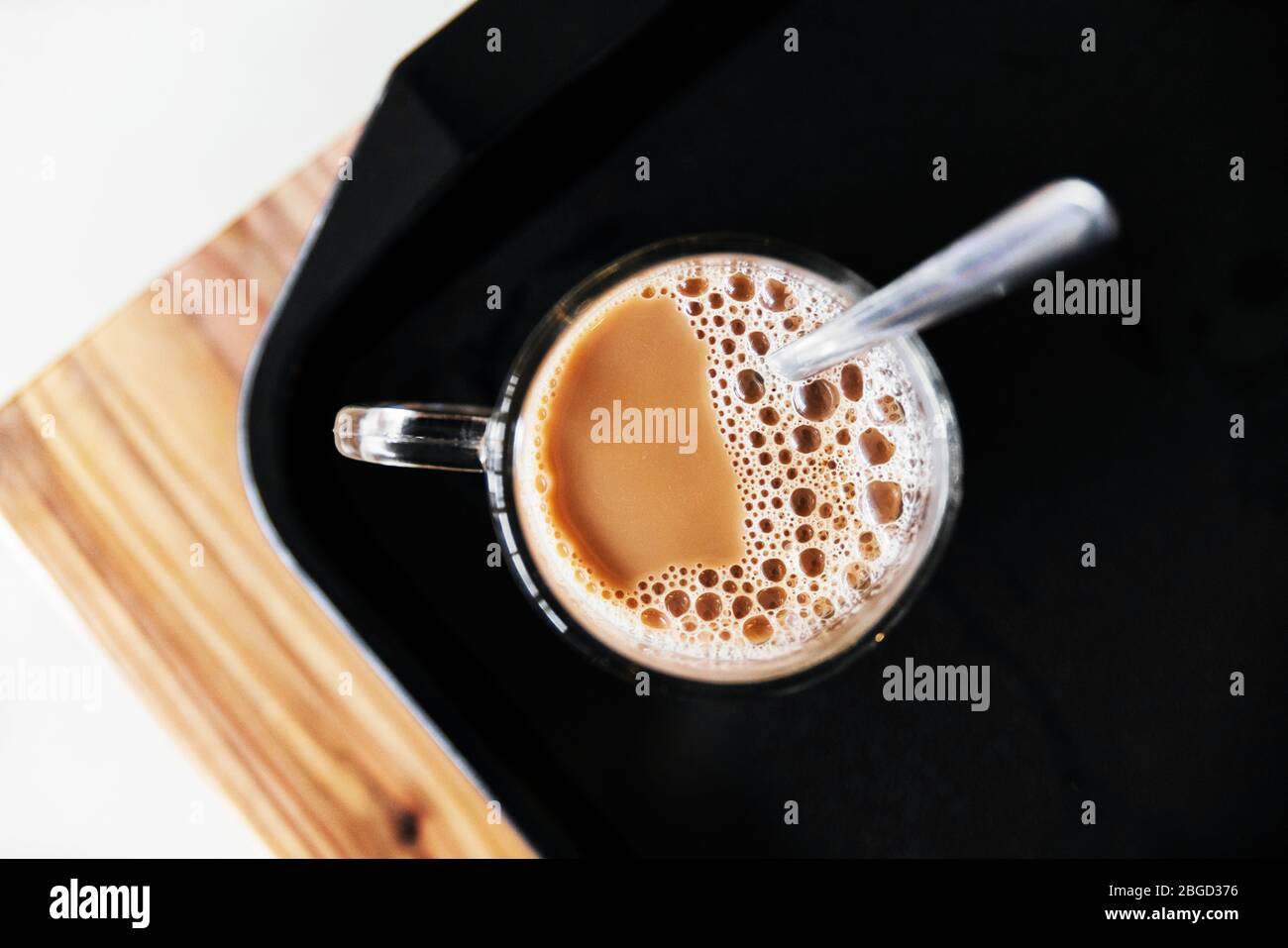 Blick von oben auf den Morgen heißen Kaffee mit Stahllöffel auf schwarzen Tablett. Hostel Morgen Kaffee Service. Stockfoto