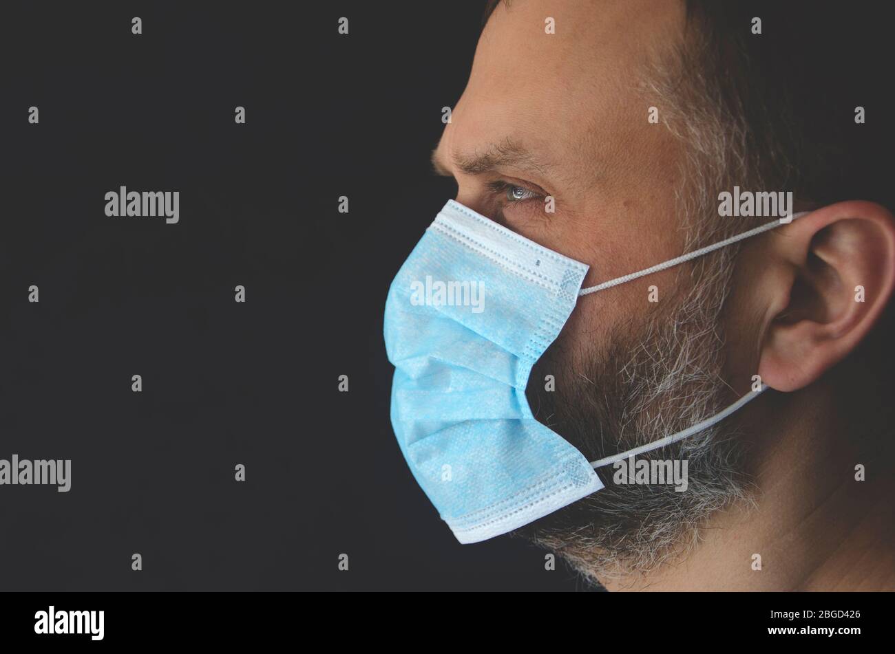 Das Gesicht eines Mannes in einer blauen medizinischen Schutzmaske Stockfoto