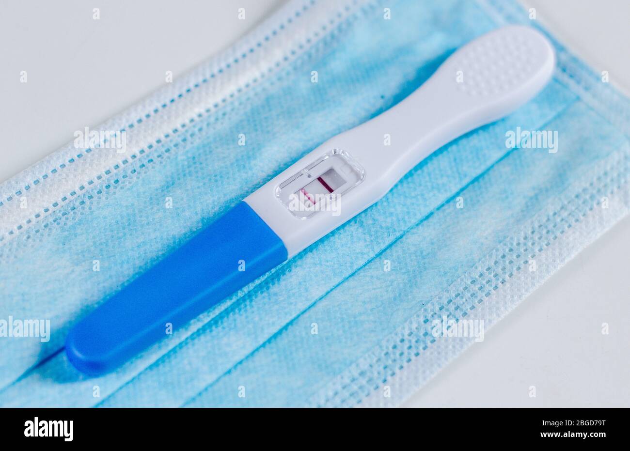 Positiver Schwangerschaftstest auf einer Gesichtsmaske. Erwartet während einer Pandemie. Gesunde Schwangerschaft. Stockfoto