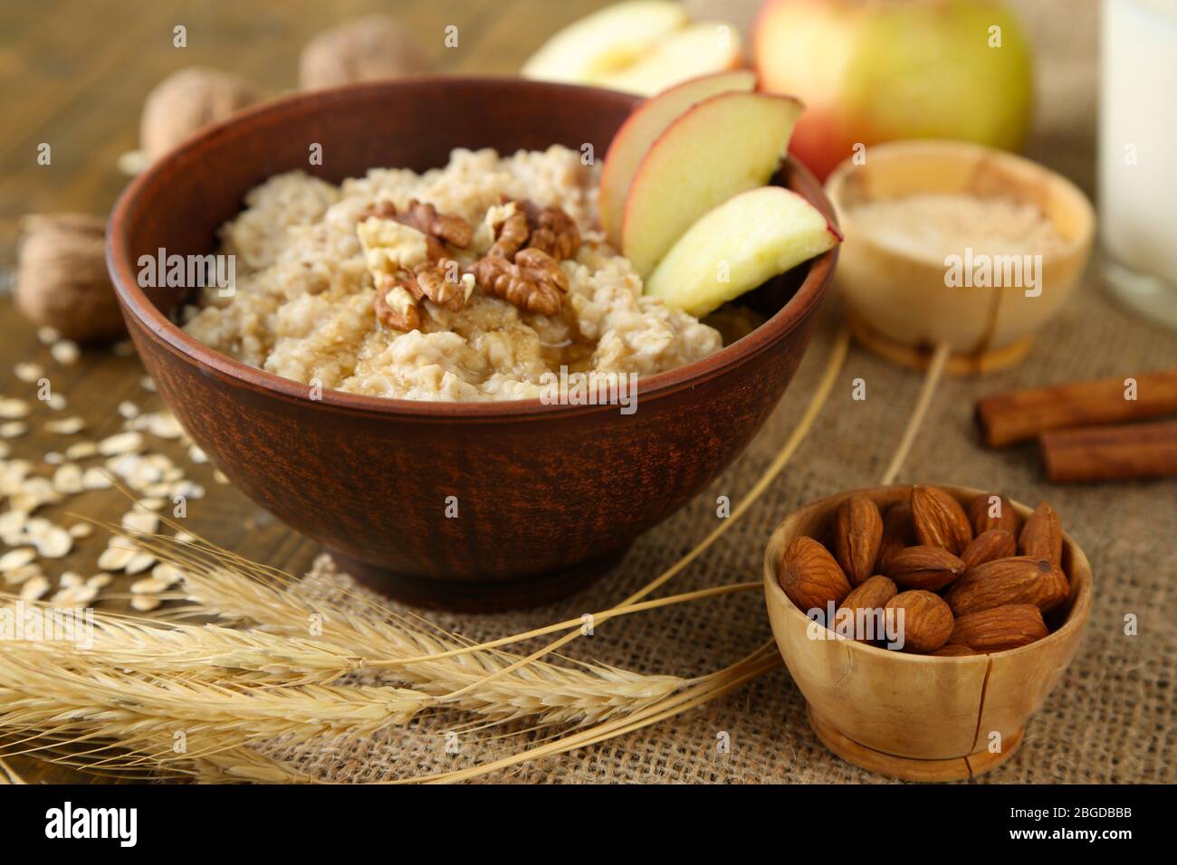 Leckere Haferflocken mit Nüssen und Äpfeln auf Holztisch Stockfoto