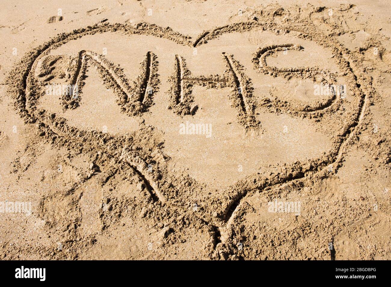 NHS geschrieben in Sand in einer Herzform, um Liebe zu illustrieren das National Health Service Konzept während Covid-19 Pandemie im Jahr 2020. Großbritannien Stockfoto