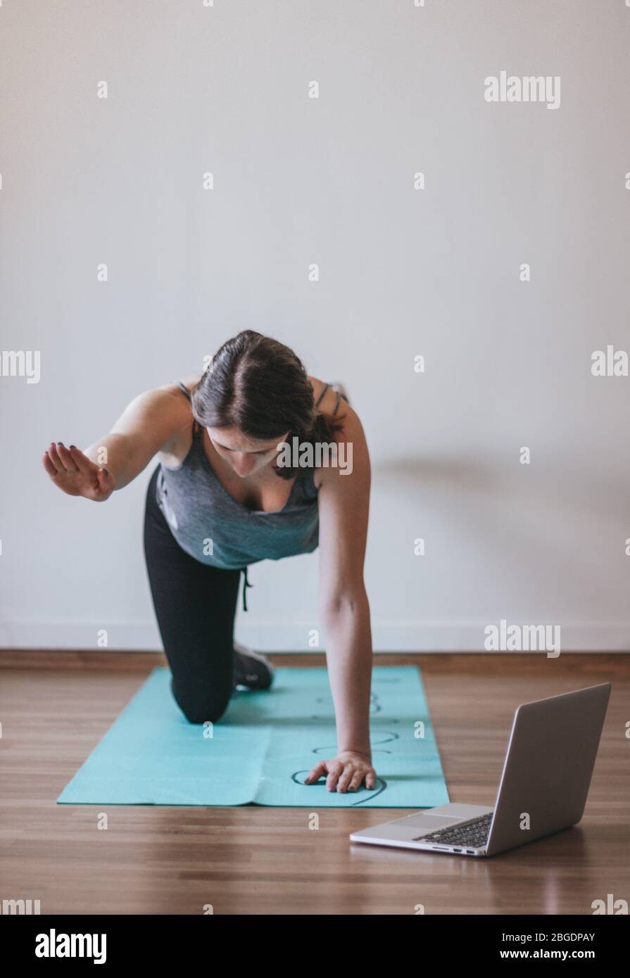 Junge Frau macht Online-Yoga zu Hause. Online-Training, Online-Training, gesund zu Hause bleiben. Stockfoto