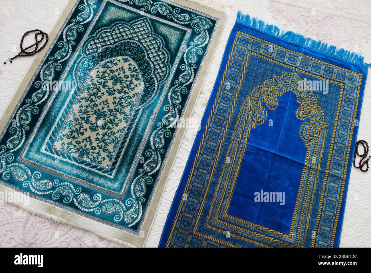 Islamische Symbole, blaue und grüne Gebetsdecken auf einem Teppich in einem Haus, Stockfoto