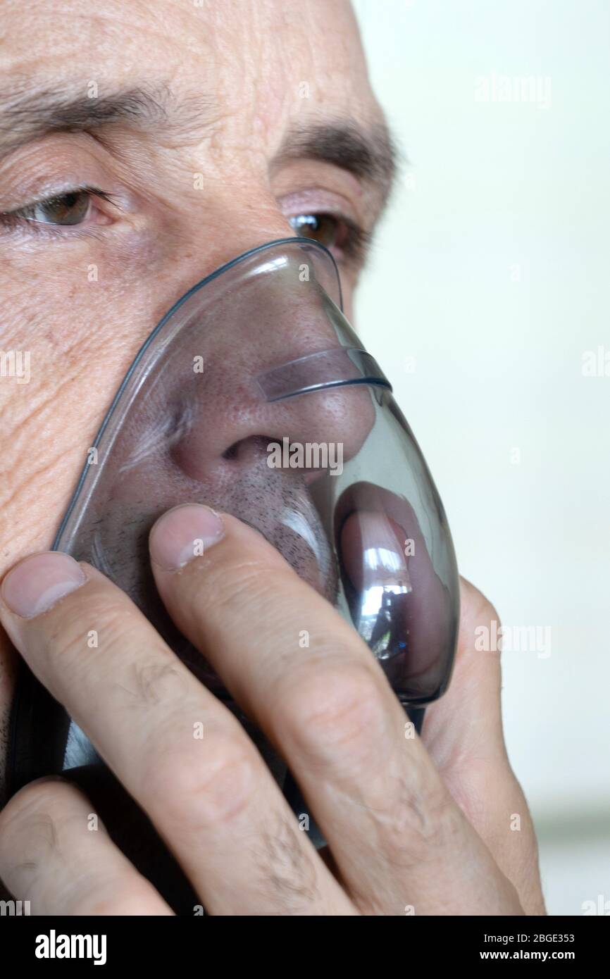 Ein Mann atmet Sauerstoff mit einer Maske. Nahaufnahme eines alten Mannes, der Inhalation macht. Stockfoto