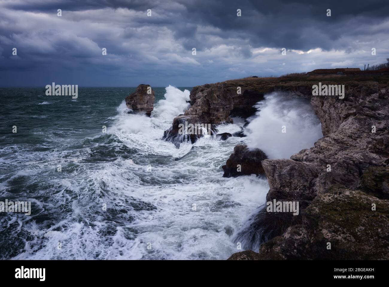 Dramatische Natur Hintergrund - große Wellen und dunklen Felsen in stürmischen Meer, stürmisches Wetter. Dramatische Szene. Kontrastierende Farben.schöne Naturlandschaft Stockfoto