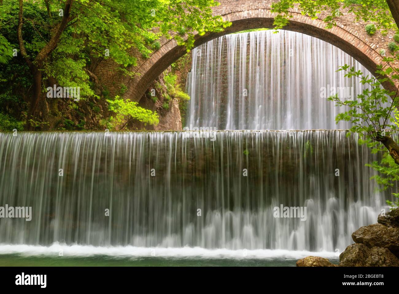 Atemberaubende Frühlingslandschaft.Paleokarya, alt, Stein, Bogenbrücke, zwischen zwei Wasserfällen. Präfektur Trikala, Thessalien, Griechenland Stockfoto