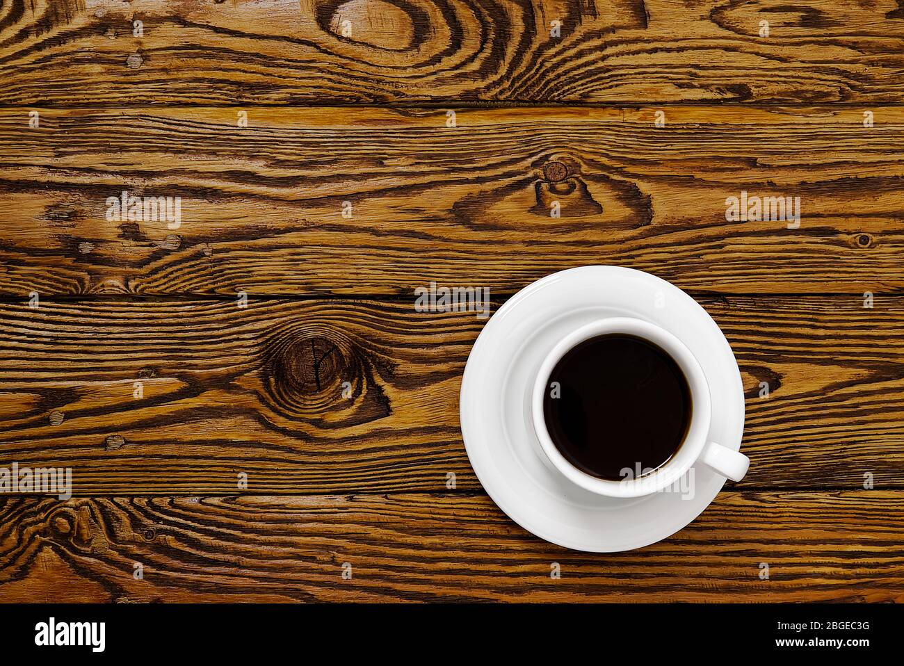 Weiße Kaffeetasse von oben auf einem alten Holztisch. Aromatischer Kaffee in weißer Tasse auf braunem Holztisch. Stockfoto