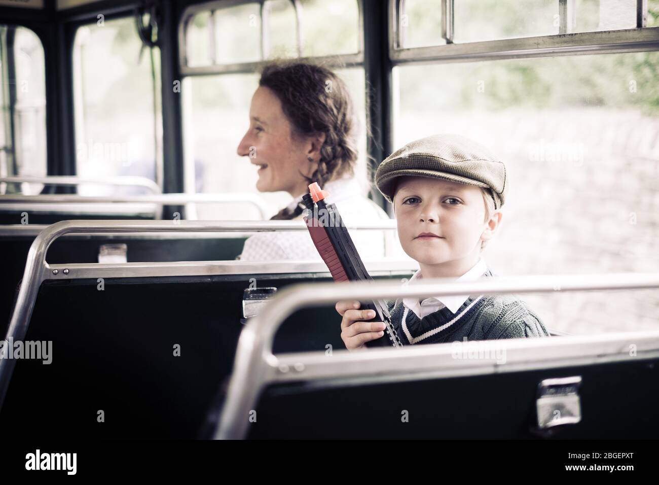 Ein kleiner Junge mit einem Spielzeug Maschinengewehr in einem Bus an der Pateley Bridge 1940er Wochenende Stockfoto