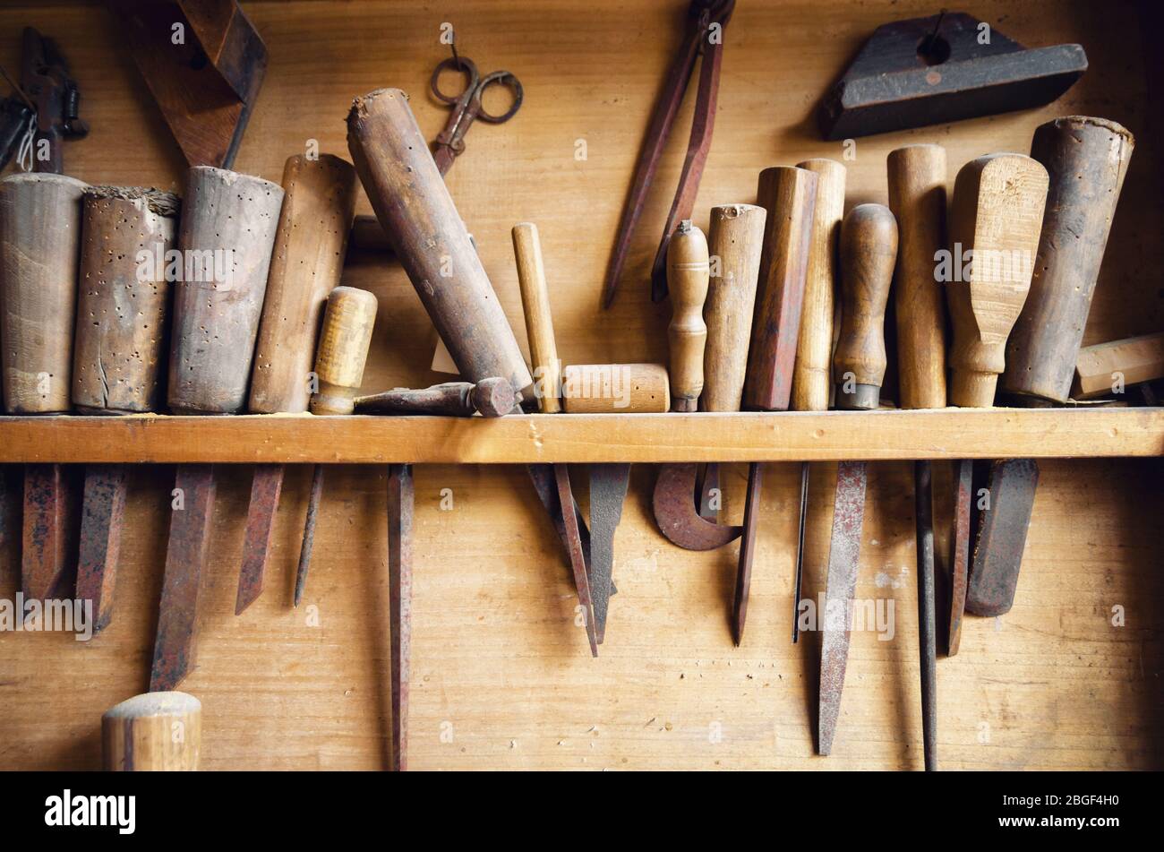 Alte alte alte Tischlerwerkzeuge hängen von der Wand einer staubigen Werkstatt Stockfoto