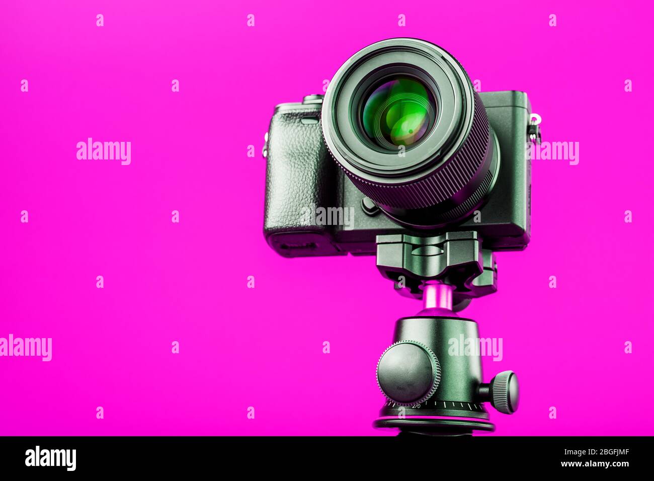 Professionelle Kamera auf einem Stativ, auf einem rosafarbenen Hintergrund. Nehmen Sie Videos und Fotos für Ihren Blog oder Bericht auf. Freier Speicherplatz, isoliert. Stockfoto