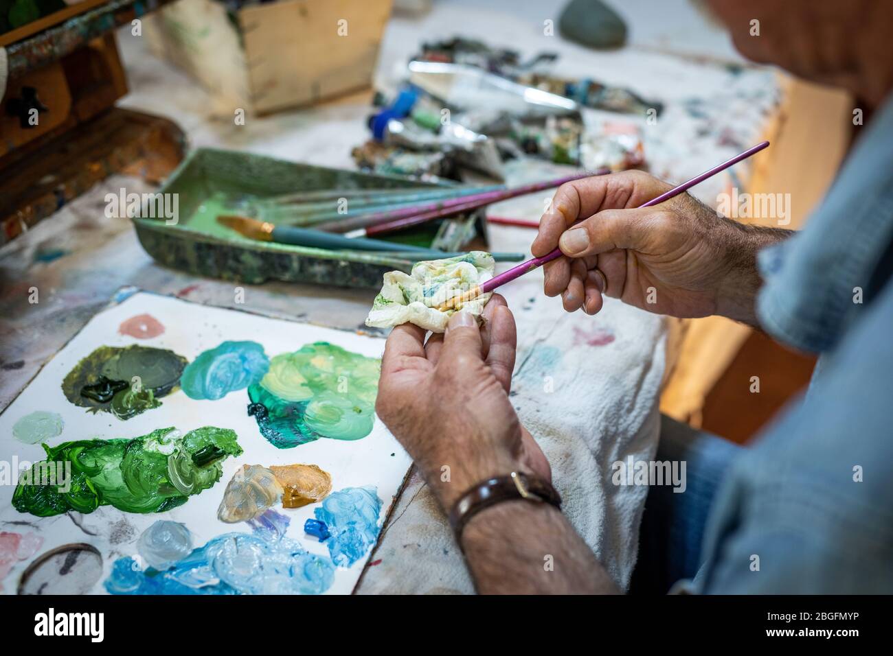 Ein Maler Senior Hände Reinigung einer Pinsel in einem Studio. Stockfoto