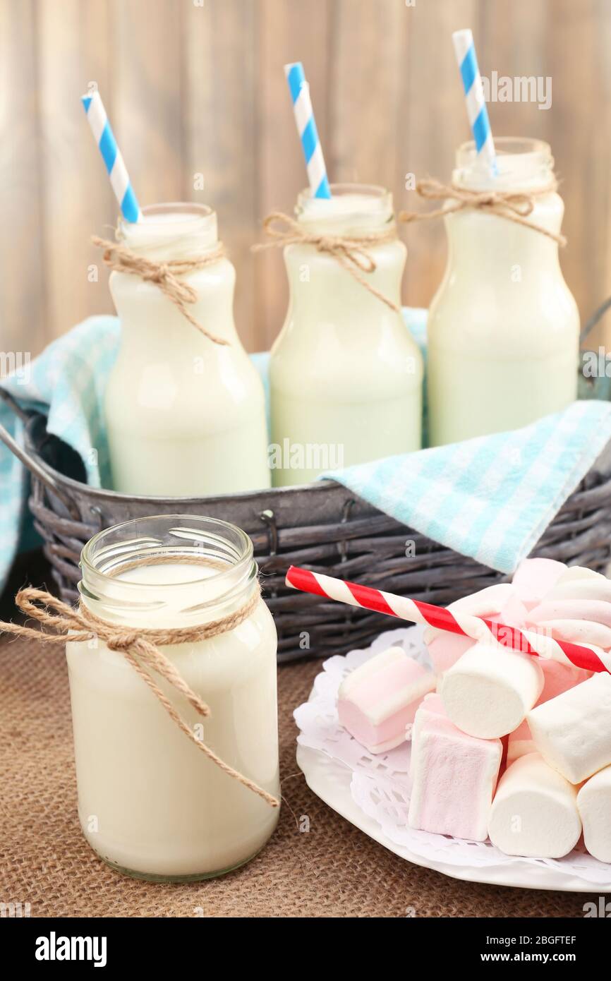 Milch in Flaschen mit Papphalmen auf dem Tisch Stockfoto