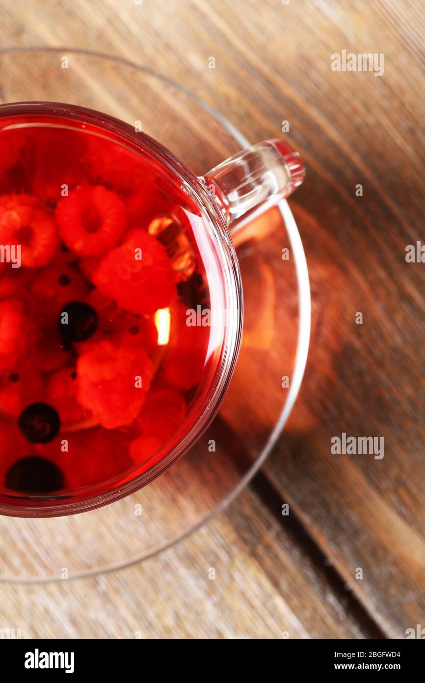 Fruchtroter Tee mit Waldbeeren in Glasbecher, auf Holzhintergrund Stockfoto