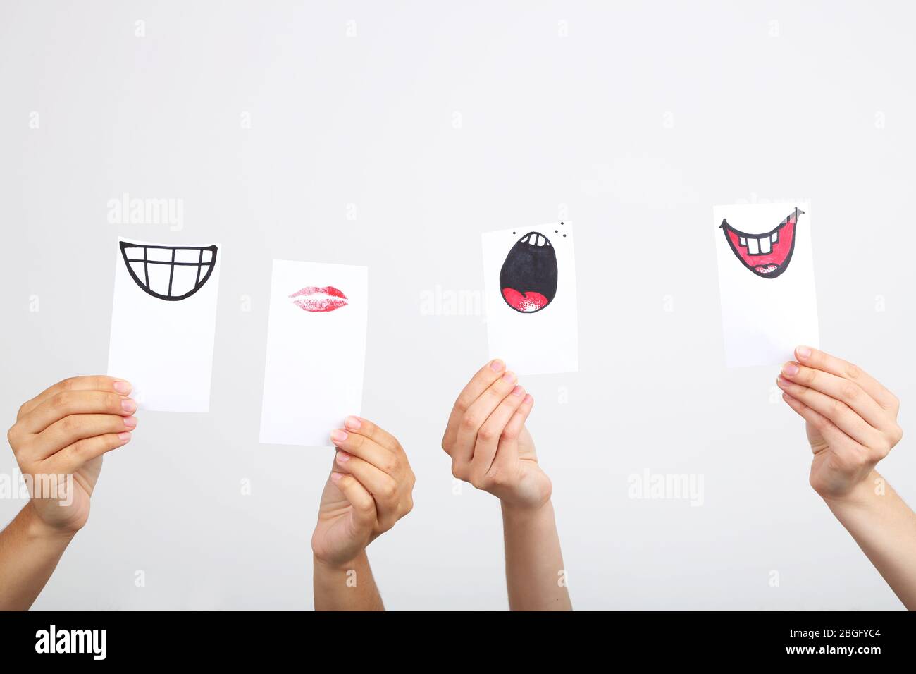 Hände halten verschiedene Smileys auf grauem Hintergrund Stockfoto