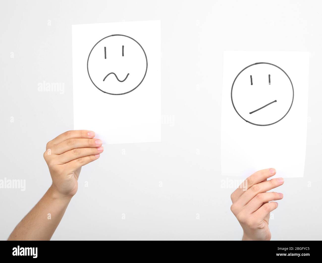 Hände halten verschiedene Smileys auf grauem Hintergrund Stockfoto