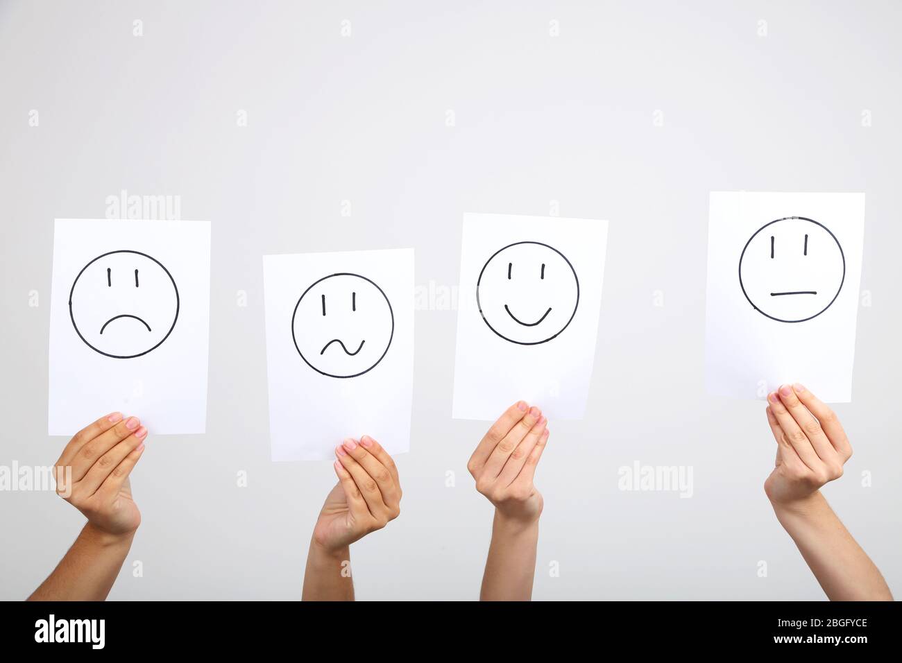 Hände halten verschiedene Smileys auf grauem Hintergrund Stockfoto