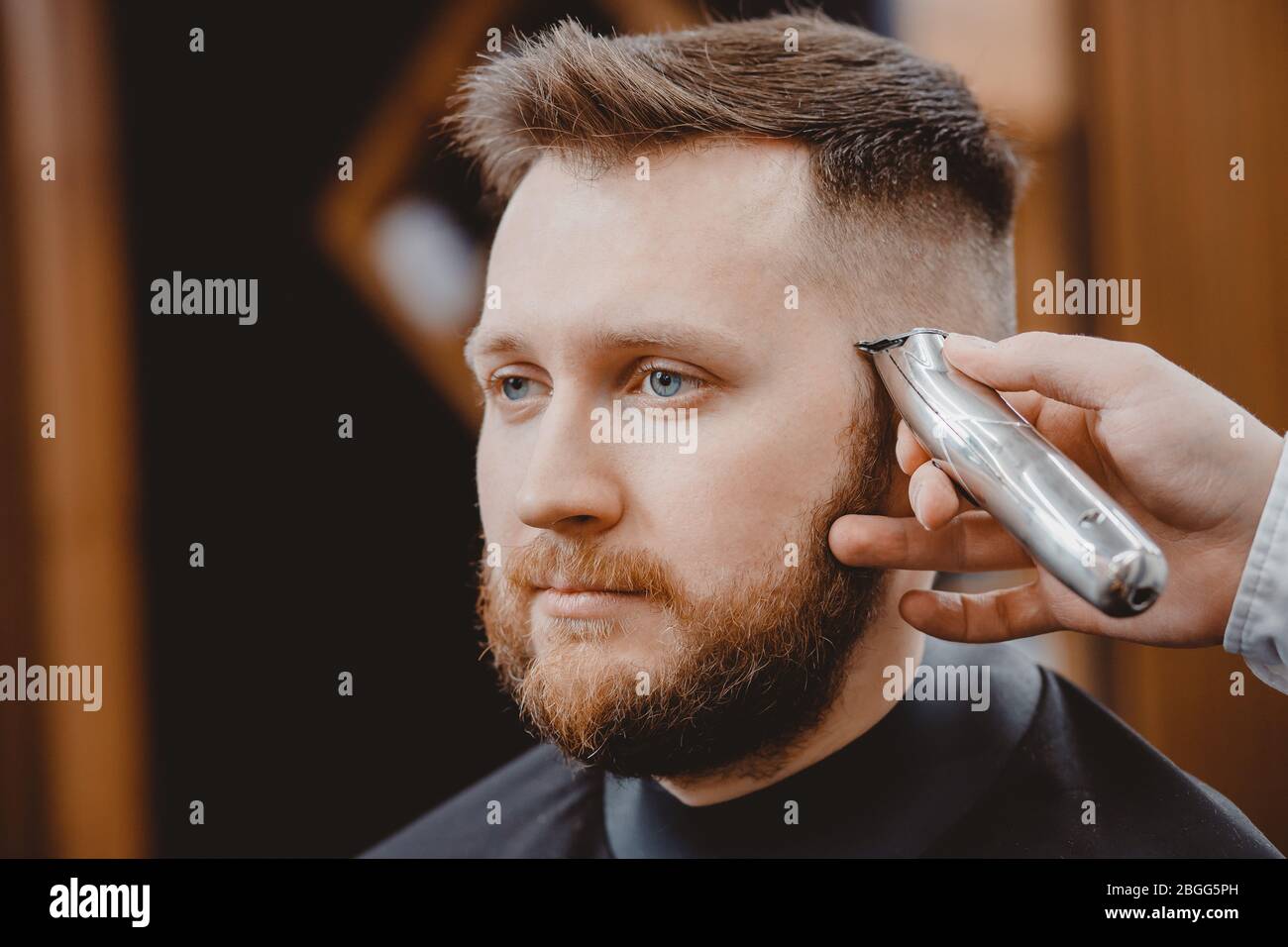 Friseursalon schneidet jungen Männern im Barbershop Haare. Barber, der mit  einem elektrischen Rasierer stylt Stockfotografie - Alamy