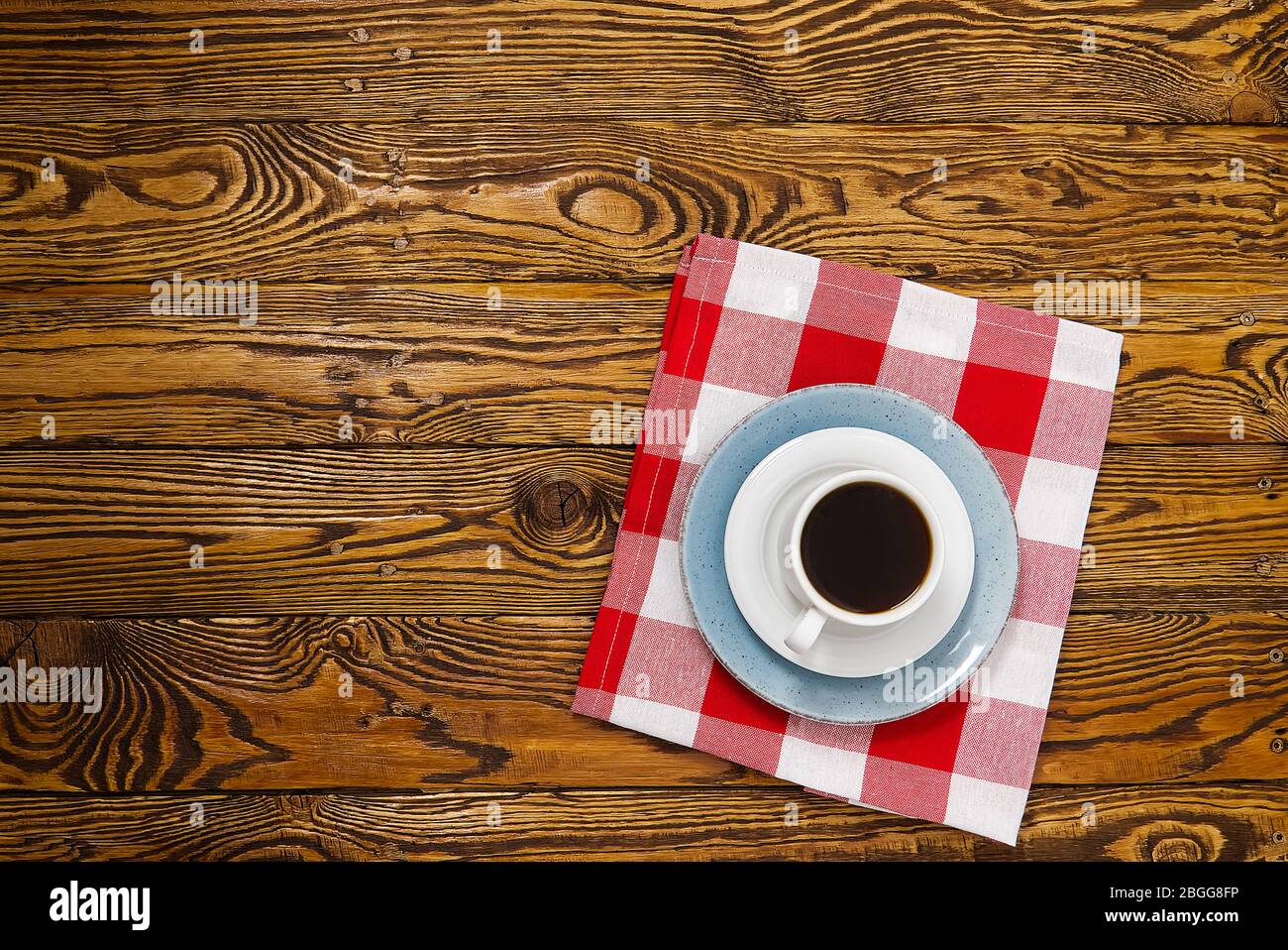 Weiße Kaffeetasse von oben auf einem alten Holztisch. Aromatischer Kaffee in weißer Tasse auf braunem Holztisch. Stockfoto
