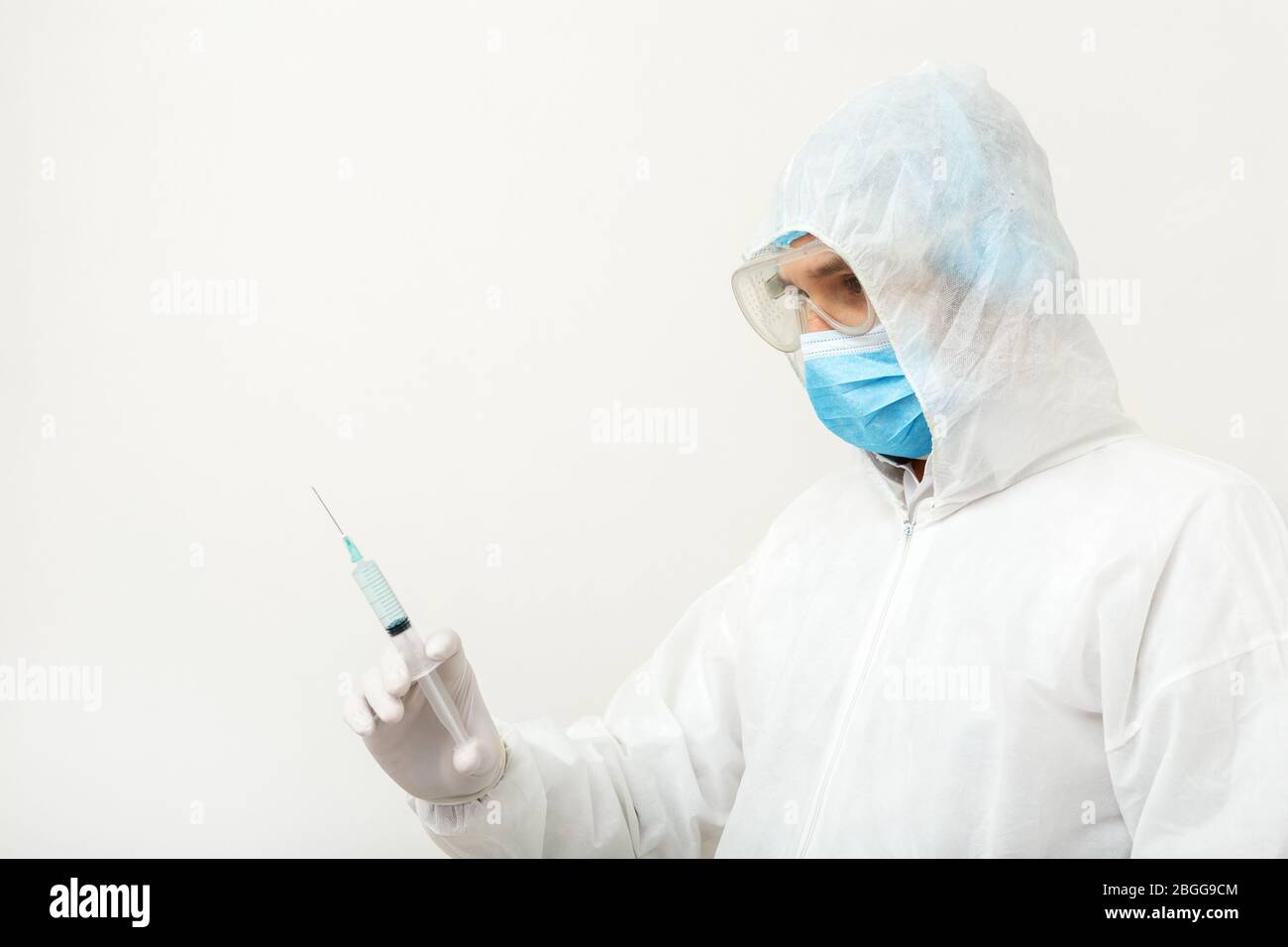 Coronavirus, Covid-19-Impfstoff. Arzt Wissenschaftler in schützenden medizinischen Anzug, biologische Gefahr, Gesichtsmaske hält Impfstoff in Spritze. Impfung Stockfoto