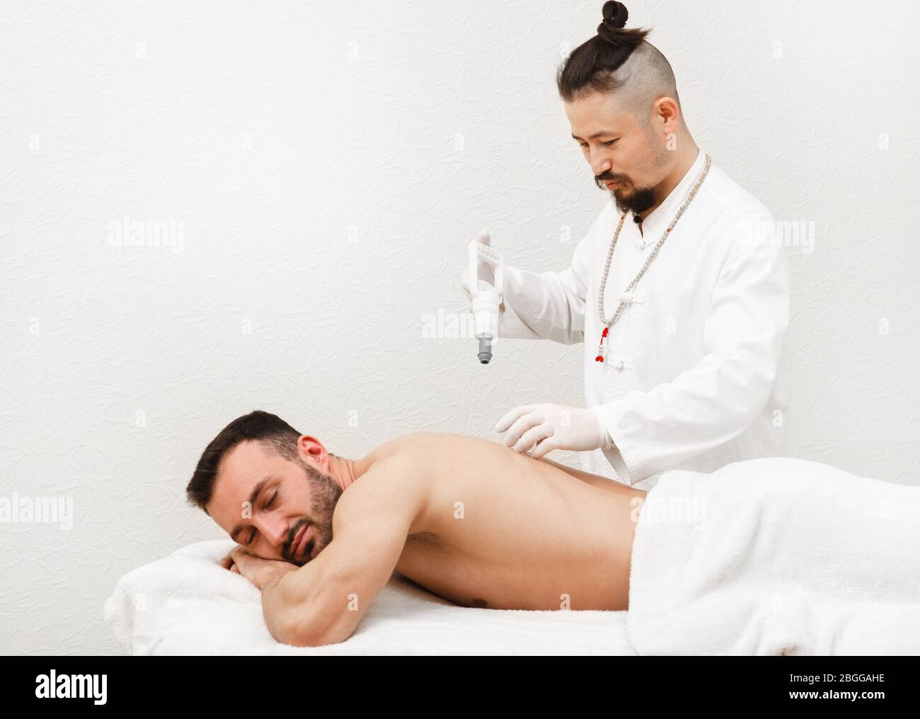 Reflexologe, der Vakuumsauger auf der Rückseite des männlichen Patienten platziert. Traditionelle orientalische Medizin Stockfoto