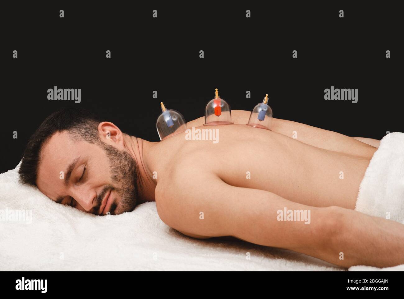 Gesundheit Erholung Mann mit Vakuumsaugern. Nahaufnahme von Vakuumbechern auf dem Rücken des Mannes auf schwarzem Hintergrund. Traditionelle orientalische Medizin. Stockfoto