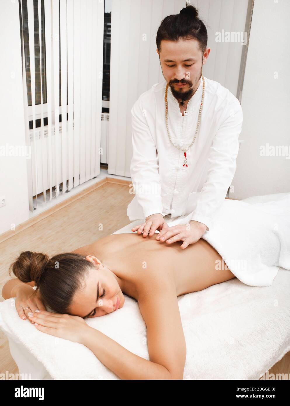 Doktor asian Race macht energetische Körpermassage. Frau bekommt Reiki-Therapie. Alternative Medizin Stockfoto