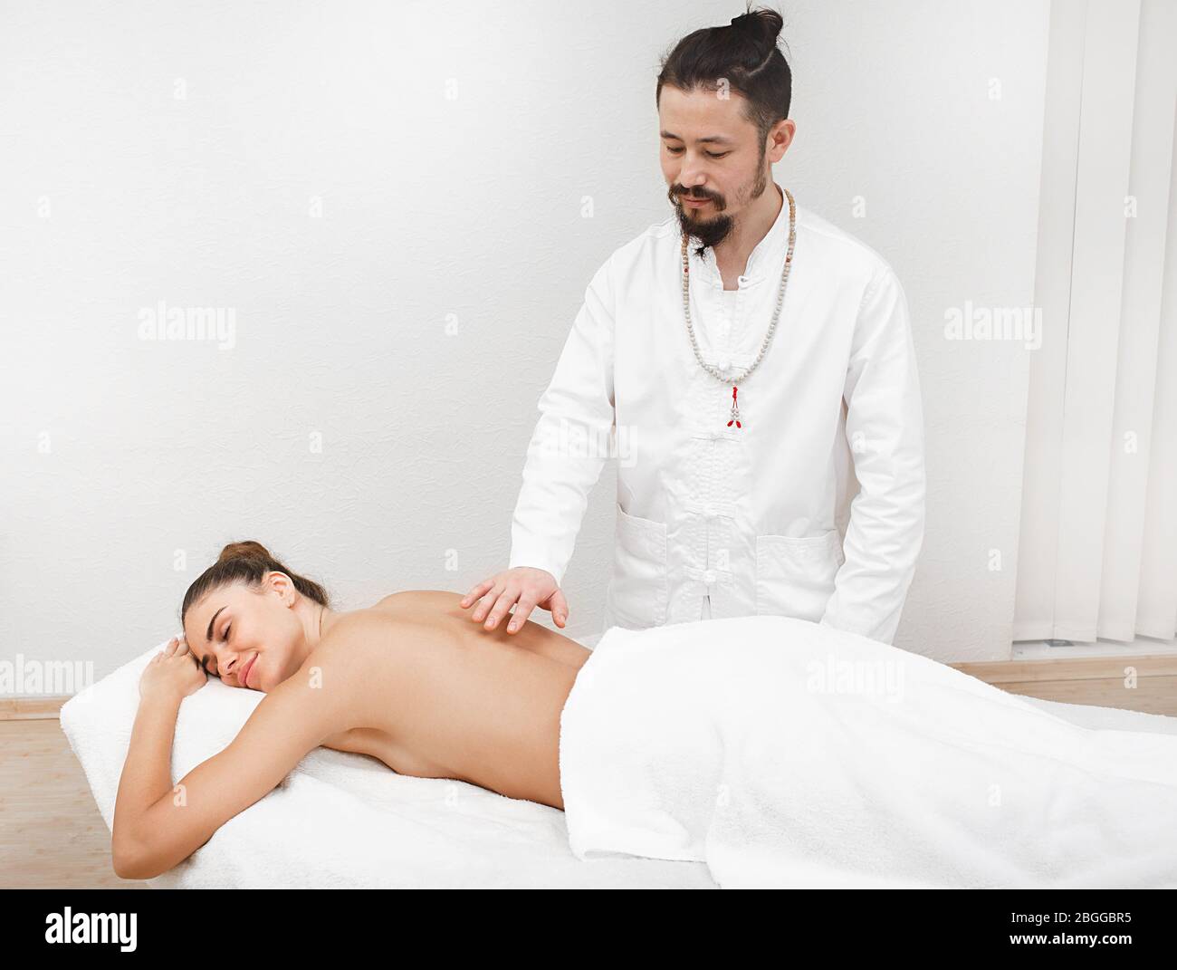 Doktor der traditionellen orientalischen Medizin, der berührungslose energetische Massage zu einer schönen Frau in einem Spa-Salon. Der Körper wird von negativem ener gereinigt Stockfoto