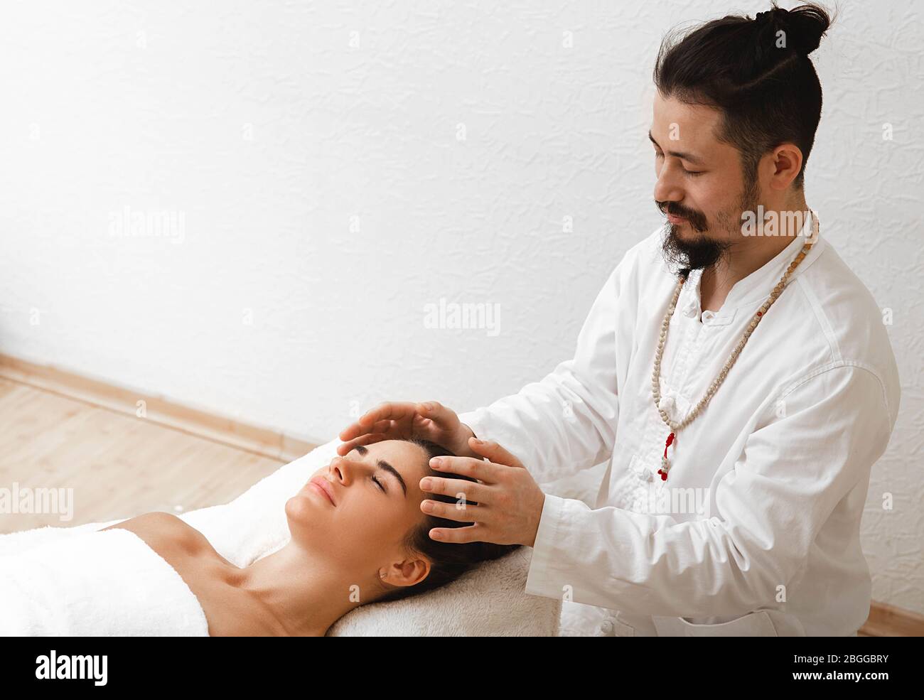 Doktor der traditionellen orientalischen Medizin mit energetischer Kopfmassage. Die energetische Massage nimmt die Energieleistung im Körper wieder auf Stockfoto