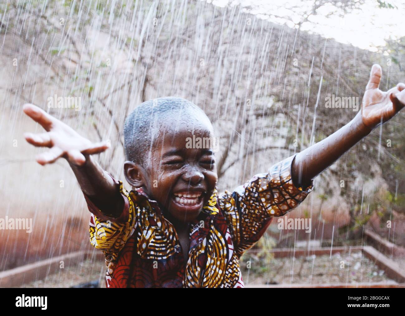 Candid Foto von fröhlichen afrikanischen Black Boy so unglaublich glücklich, Wasser aus Regen in der Trockenzeit zu bekommen Stockfoto