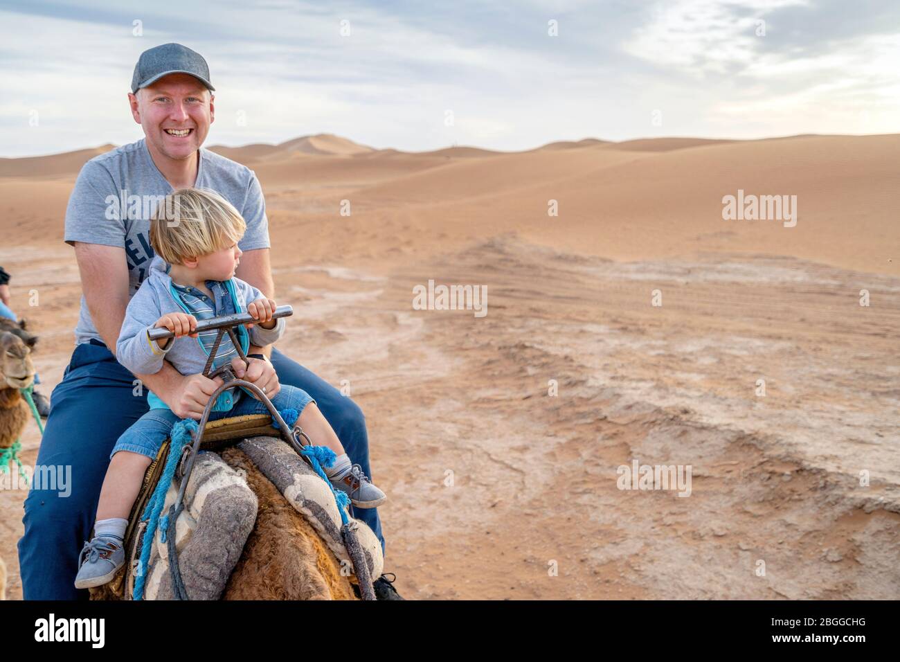 Vater und sein zweijähriger Sohn reiten auf einem Kamel auf dem Sand der Sahara, Marokko, Afrika Stockfoto