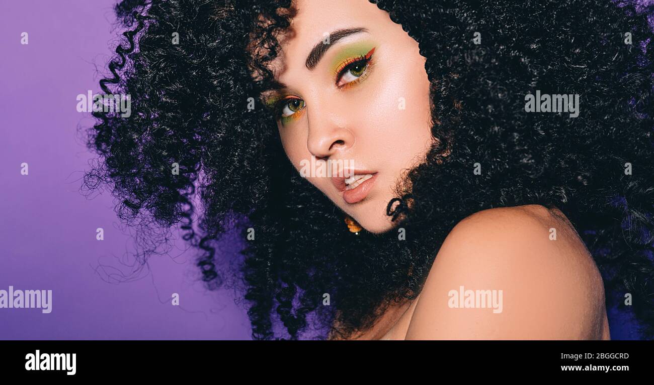 Porträt einer rastafarian Frau mit afro Frisur und Farbe Make-up auf einem violetten Hintergrund. Stockfoto
