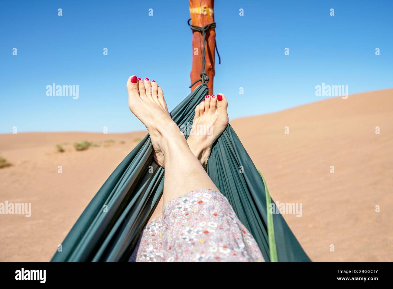 Junge Frau in der grünen Hängematte mit Blick auf Sanddünen der Sahara Wüste, Marokko, Afrika entspannen Stockfoto