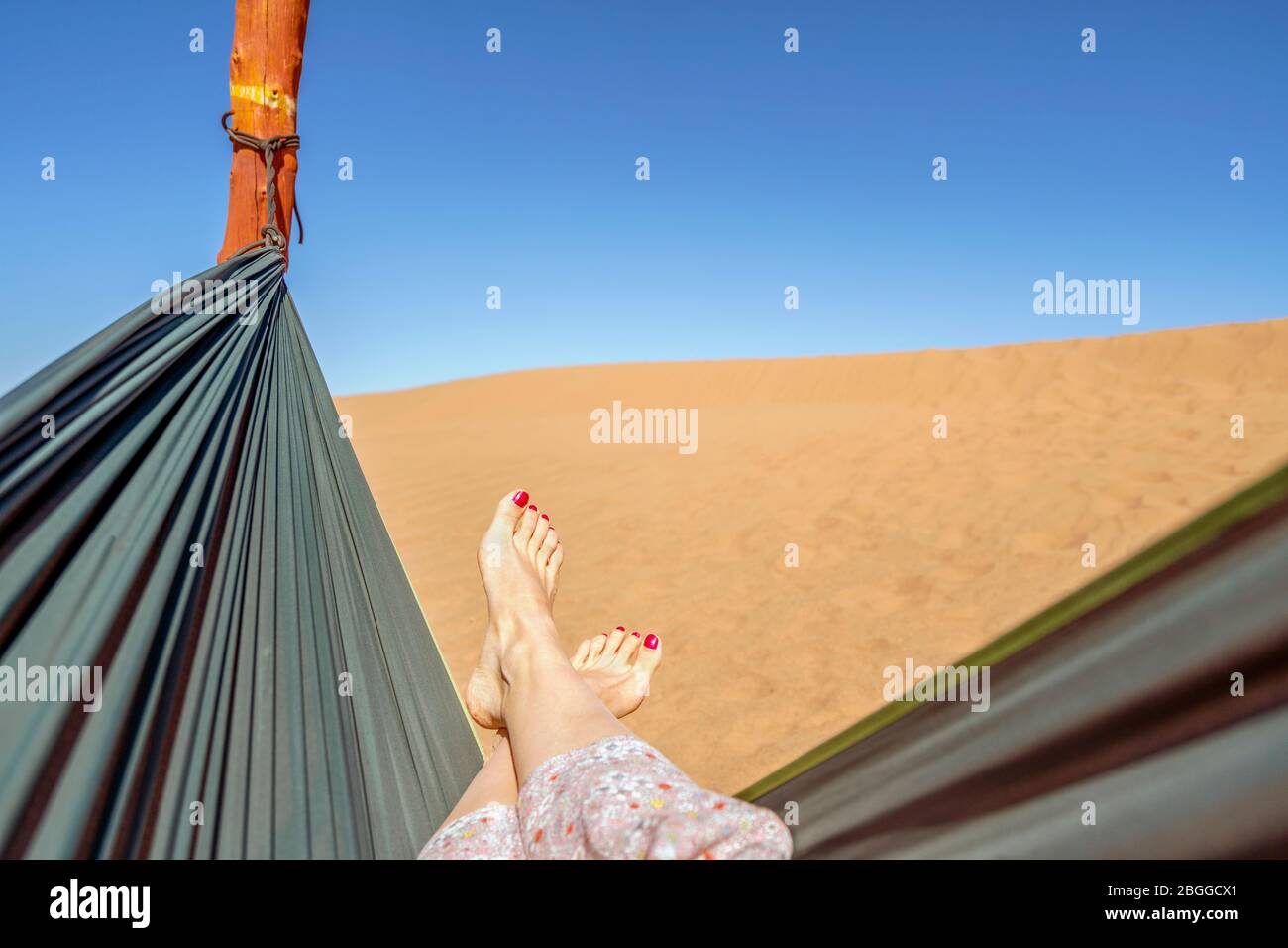 Junge Frau in der grünen Hängematte mit Blick auf Sanddünen der Sahara Wüste, Marokko, Afrika entspannen Stockfoto