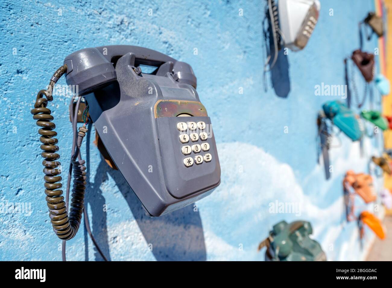 An der blauen Wand in Marokko hängen viele alte, bunte Telefone Stockfoto