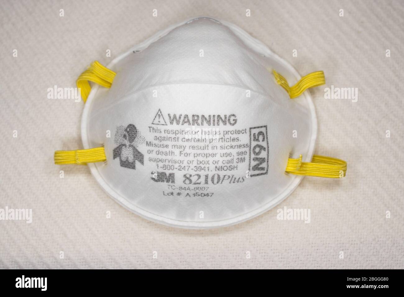 Eine 3M Atemschutzmaske Typ N95 zum Schutz vor Verschmutzung und Krankheiten, wie Grippe und Viren, Coronavirus, isoliert auf einer weißen Krankenhausdecke. Stockfoto
