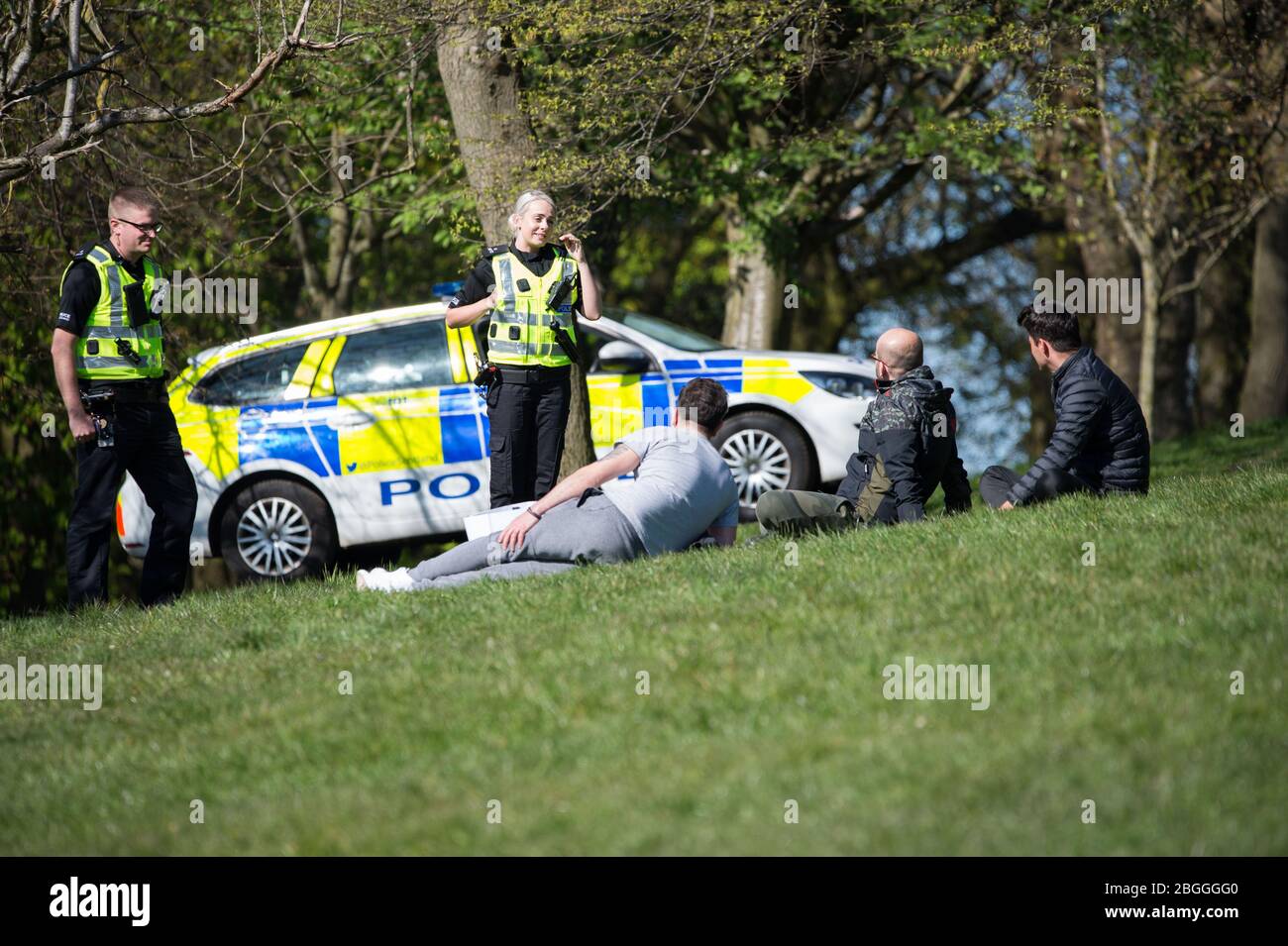 Glasgow, Großbritannien. April 2020. Im Bild: Eine Polizeiwache spricht mit Menschen, die auf dem Gras liegen und sich sonnen und sie weiterbewegen, während sie die Coronavirus-Gesetzgebung von einer Stunde Bewegung pro Tag durchsetzen. Szenen aus dem Kelvingrove Park in Glasgow während der Sperrung des Coronavirus (COVID-19). Quelle: Colin Fisher/Alamy Live News Stockfoto