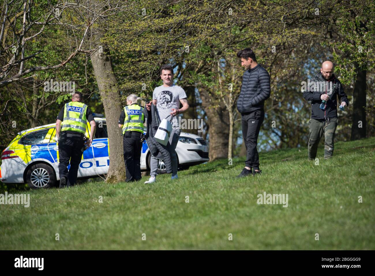 Glasgow, Großbritannien. April 2020. Im Bild: Eine Polizeiwache spricht mit Menschen, die auf dem Gras liegen und sich sonnen und sie weiterbewegen, während sie die Coronavirus-Gesetzgebung von einer Stunde Bewegung pro Tag durchsetzen. Szenen aus dem Kelvingrove Park in Glasgow während der Sperrung des Coronavirus (COVID-19). Quelle: Colin Fisher/Alamy Live News Stockfoto